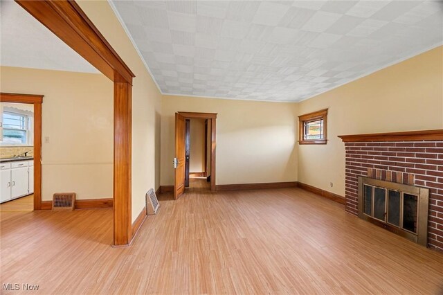 57 Charles Ave, Boardman, OH 44512 - unfurnished living room with light wood-style flooring, a brick fireplace, and crown molding
