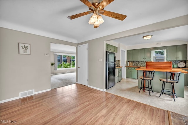 484 E 319th St, Willowick, OH 44095 - kitchen with green cabinets, freestanding refrigerator, decorative backsplash, a ceiling fan, and light wood-style floors