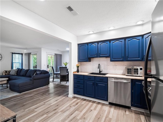 1217 W River Rd N Unit A3, Elyria, OH 44035 - kitchen featuring stainless steel dishwasher, blue cabinets, freestanding refrigerator, light wood-style floors, and decorative backsplash