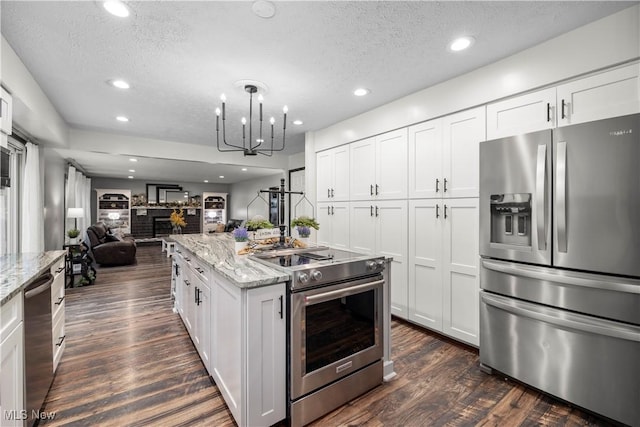 26938 Tall Oaks Trl, Olmsted Twp, OH 44138 - kitchen with stainless steel appliances, open floor plan, dark wood-style flooring, a textured ceiling, and light stone countertops