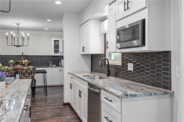 26938 Tall Oaks Trl, Olmsted Twp, OH 44138 - kitchen with appliances with stainless steel finishes, backsplash, white cabinets, a chandelier, and ornamental molding