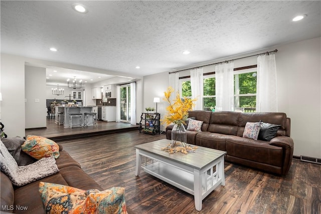 26938 Tall Oaks Trl, Olmsted Twp, OH 44138 - living room with a chandelier, a textured ceiling, recessed lighting, plenty of natural light, and dark wood-type flooring