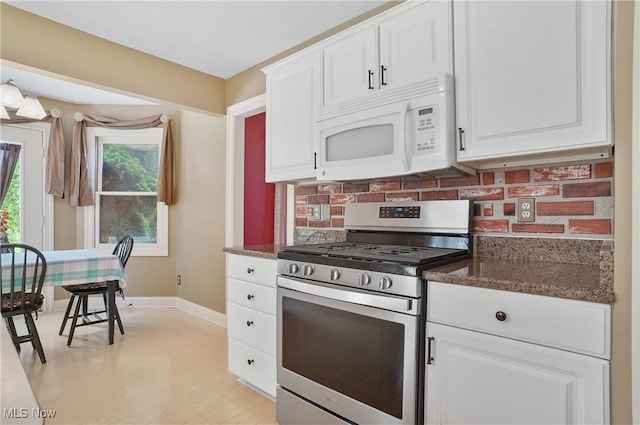 8883 Michaels Ln, Broadview Heights, OH 44147 - kitchen with white microwave, gas range, white cabinetry, decorative backsplash, and dark stone counters