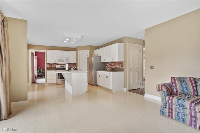 8883 Michaels Ln, Broadview Heights, OH 44147 - kitchen featuring stainless steel appliances, decorative backsplash, white cabinets, and a center island with sink