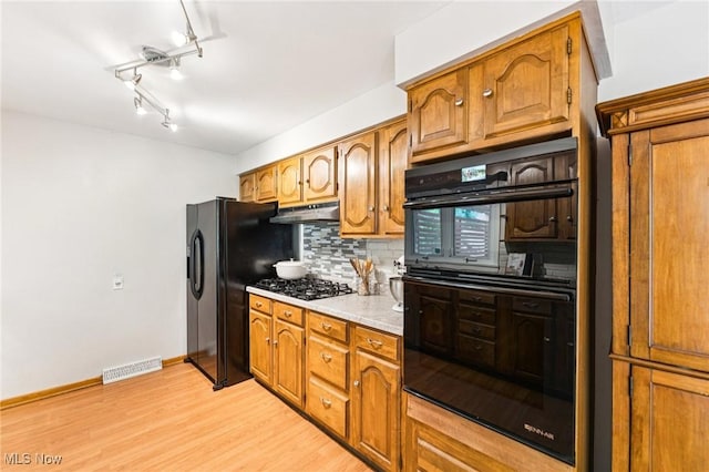 129 Whitman Blvd, Elyria, OH 44035 - kitchen featuring black appliances, tasteful backsplash, light wood-type flooring, light countertops, and brown cabinetry