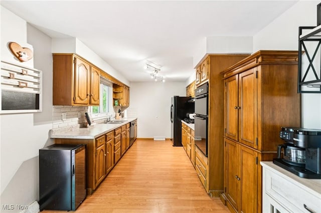 129 Whitman Blvd, Elyria, OH 44035 - kitchen featuring black appliances, light wood finished floors, brown cabinetry, light countertops, and backsplash