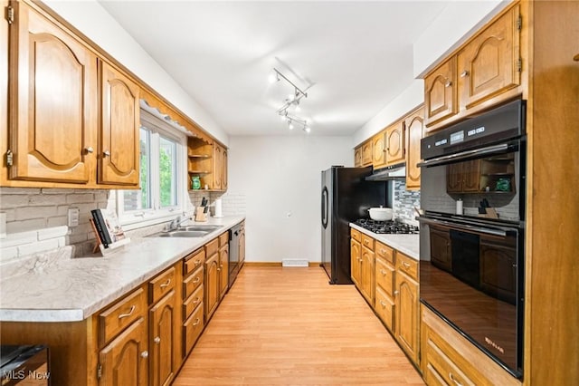 129 Whitman Blvd, Elyria, OH 44035 - kitchen with black appliances, under cabinet range hood, light wood finished floors, backsplash, and light countertops