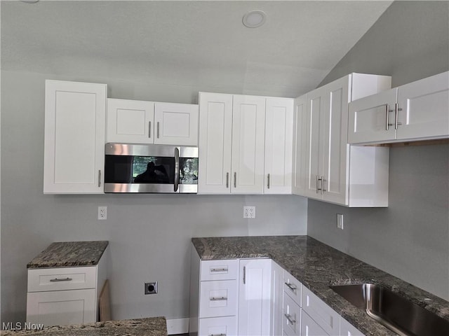 2500 Redgate Ln, Austintown, OH 44511 - kitchen featuring stainless steel microwave, dark stone counters, white cabinetry, and lofted ceiling