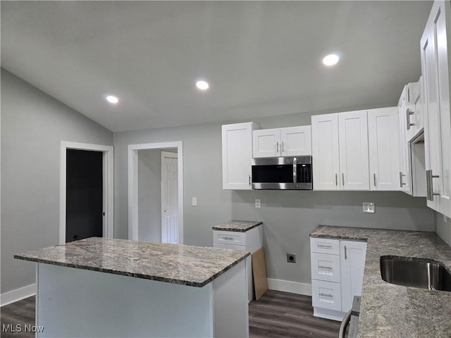 2500 Redgate Ln, Austintown, OH 44511 - kitchen featuring stainless steel microwave, dark wood finished floors, dark stone countertops, a center island, and white cabinetry