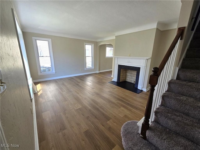 26313 Oriole Ave, Euclid, OH 44132 - unfurnished living room featuring arched walkways, wood finished floors, plenty of natural light, and stairway