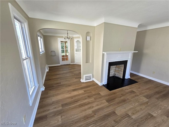 26313 Oriole Ave, Euclid, OH 44132 - unfurnished living room with arched walkways, a chandelier, wood finished floors, and a fireplace with flush hearth