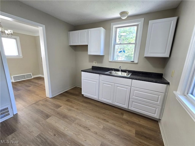 26313 Oriole Ave, Euclid, OH 44132 - kitchen featuring white cabinets, dark countertops, light wood finished floors, and a chandelier