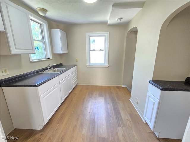 26313 Oriole Ave, Euclid, OH 44132 - kitchen with white cabinets, dark countertops, light wood finished floors, and arched walkways