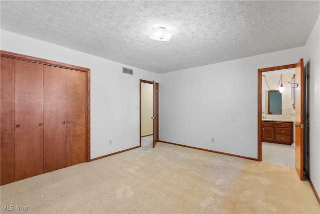 120 Vineyard Way, Doylestown, OH 44230 - unfurnished bedroom featuring light colored carpet, a closet, a textured ceiling, and connected bathroom