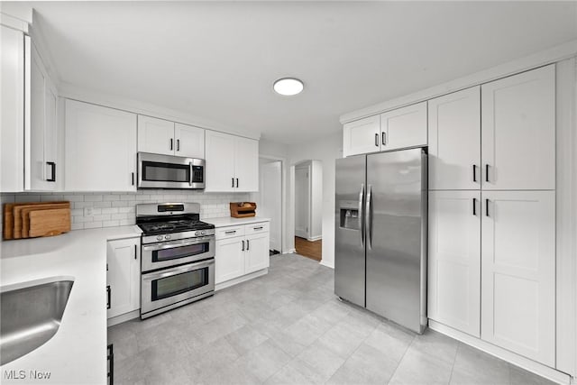 1361 Plainfield Rd, South Euclid, OH 44121 - kitchen with appliances with stainless steel finishes, light countertops, white cabinets, and backsplash