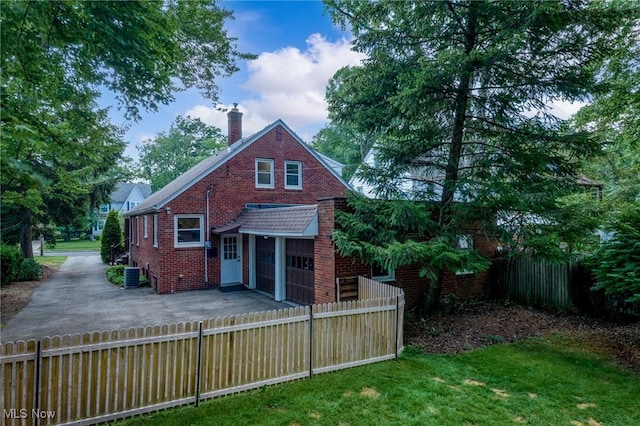 1361 Plainfield Rd, South Euclid, OH 44121 - back of property featuring driveway, an attached garage, a fenced backyard, a chimney, and brick siding