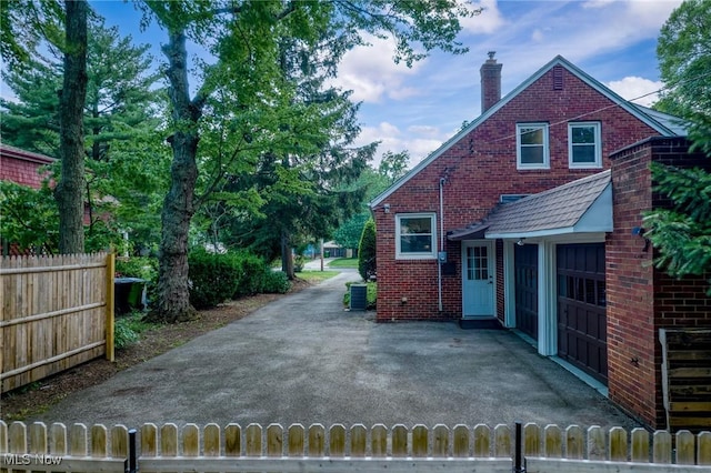 1361 Plainfield Rd, South Euclid, OH 44121 - view of side of home with a chimney, brick siding, and driveway