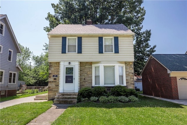 234 E 218th St, Euclid, OH 44123 - colonial home featuring stone siding, a front lawn, a chimney, and a garage