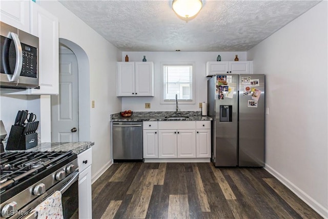 234 E 218th St, Euclid, OH 44123 - kitchen with appliances with stainless steel finishes, dark wood finished floors, dark stone countertops, a textured ceiling, and white cabinets