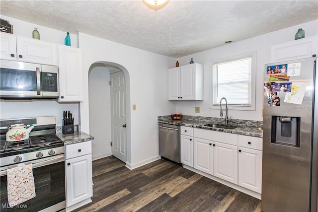 234 E 218th St, Euclid, OH 44123 - kitchen with appliances with stainless steel finishes, dark wood-type flooring, dark stone counters, white cabinets, and arched walkways