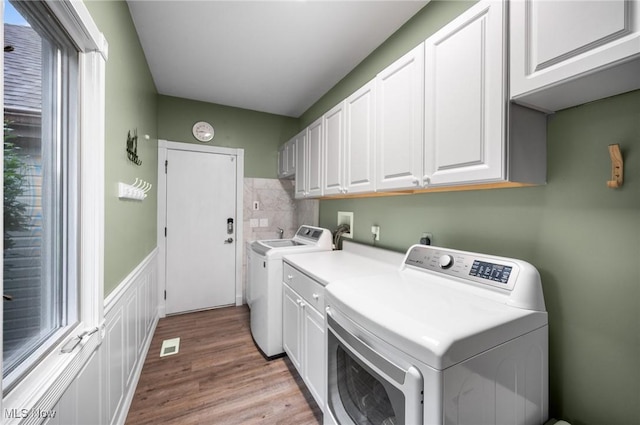 8985 Williams Rd, Chardon, OH 44024 - laundry area featuring cabinet space, wood finished floors, a wainscoted wall, and washing machine and dryer