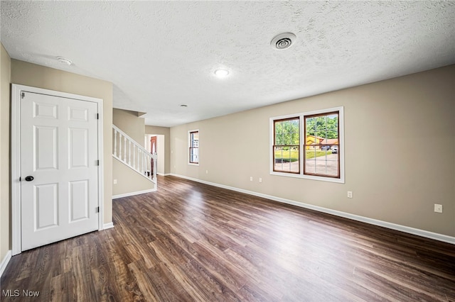 5411 W Heisley Rd, Mentor, OH 44060 - empty room featuring dark wood-style floors, stairway, a textured ceiling, and a smoke detector