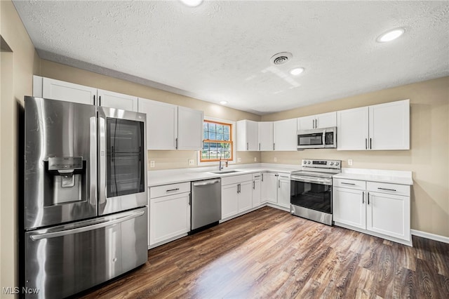 5411 W Heisley Rd, Mentor, OH 44060 - kitchen featuring stainless steel appliances, a textured ceiling, light countertops, white cabinets, and dark wood-style flooring