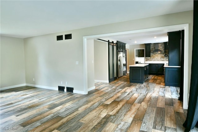 191 Maple Leaf Dr, Hubbard, OH 44425 - unfurnished living room with a barn door, wood finished floors, and recessed lighting