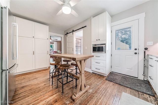 128 Forest Hill Dr, Avon Lake, OH 44012 - kitchen with appliances with stainless steel finishes, a ceiling fan, a barn door, and white cabinetry