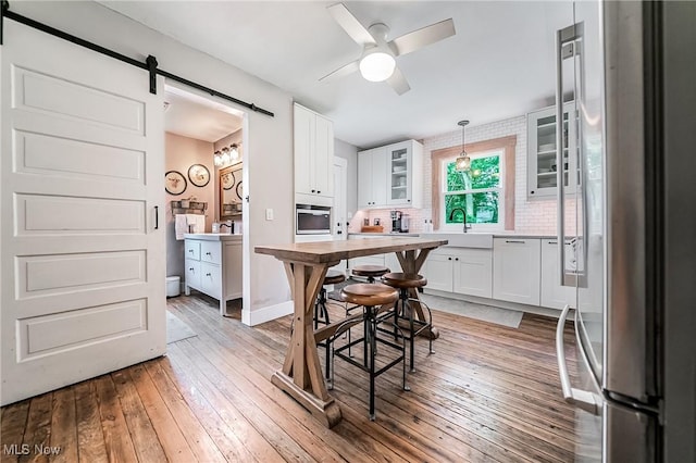 128 Forest Hill Dr, Avon Lake, OH 44012 - dining room featuring a barn door, light wood-style flooring, and ceiling fan