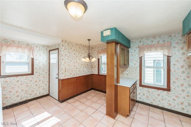 3817 Washington Park Blvd, Newburgh Heights, OH 44105 - kitchen with a chandelier, light countertops, decorative light fixtures, brown cabinets, and wallpapered walls
