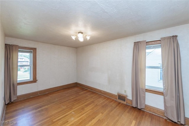 3817 Washington Park Blvd, Newburgh Heights, OH 44105 - empty room with light wood finished floors, a chandelier, and a textured ceiling