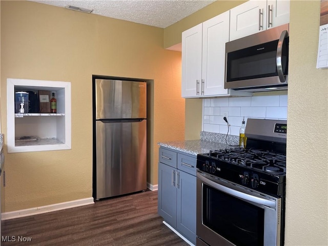 35958 Hiawatha Blvd, Eastlake, OH 44095 - kitchen featuring appliances with stainless steel finishes, white cabinets, dark wood-style floors, decorative backsplash, and light stone counters