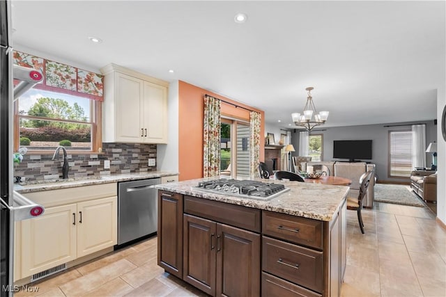 3100 Ravineview Cir, Stow, OH 44224 - kitchen featuring stainless steel appliances, cream cabinets, decorative backsplash, open floor plan, and a chandelier