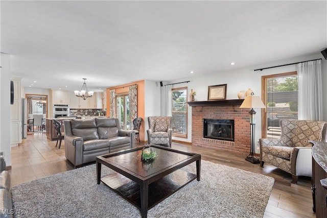 3100 Ravineview Cir, Stow, OH 44224 - living area featuring a brick fireplace, a chandelier, healthy amount of natural light, light wood-type flooring, and recessed lighting