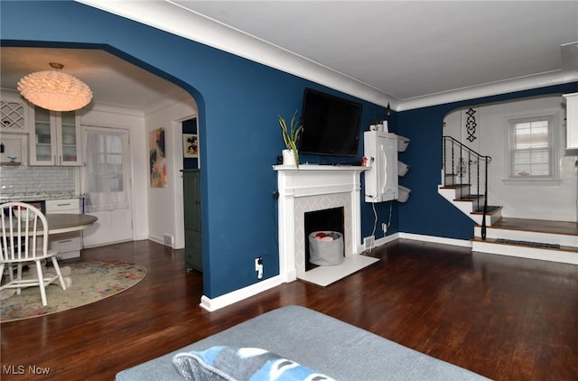 3921 Grosvenor Rd, South Euclid, OH 44118 - living room featuring arched walkways, wood finished floors, a fireplace, stairway, and ornamental molding
