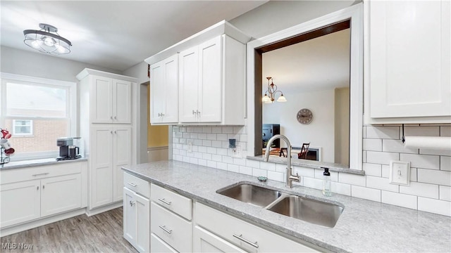 87 Holcomb Ave, Mogadore, OH 44260 - kitchen featuring backsplash, white cabinets, light stone counters, and light wood-style flooring