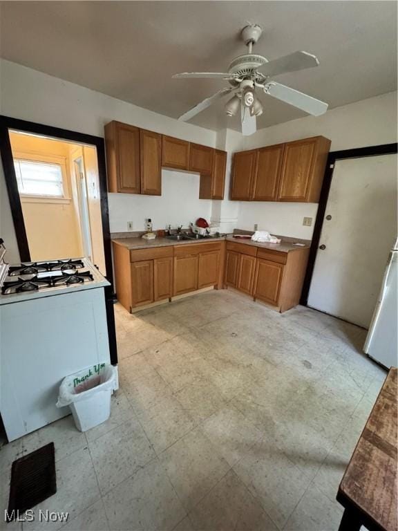 699 E 156th St, Cleveland, OH 44110 - kitchen with gas range gas stove, ceiling fan, brown cabinetry, and light floors