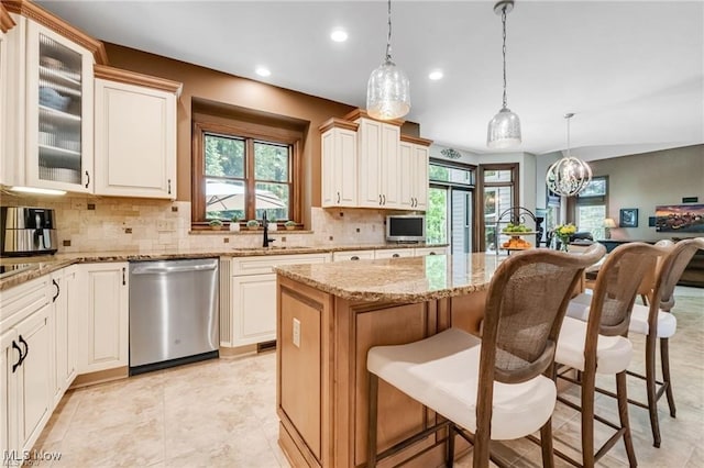 32305 Monaco Pl, Avon Lake, OH 44012 - kitchen with dishwasher, decorative backsplash, a kitchen bar, a center island, and light stone countertops