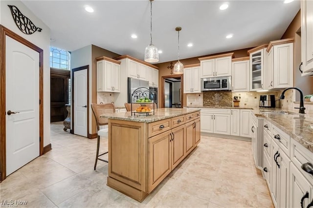 32305 Monaco Pl, Avon Lake, OH 44012 - kitchen featuring appliances with stainless steel finishes, backsplash, a kitchen island, light stone countertops, and a breakfast bar
