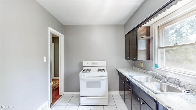 1672 Battery B St, Akron, OH 44305 - kitchen featuring white range with gas stovetop, light tile patterned floors, light countertops, and dark brown cabinets