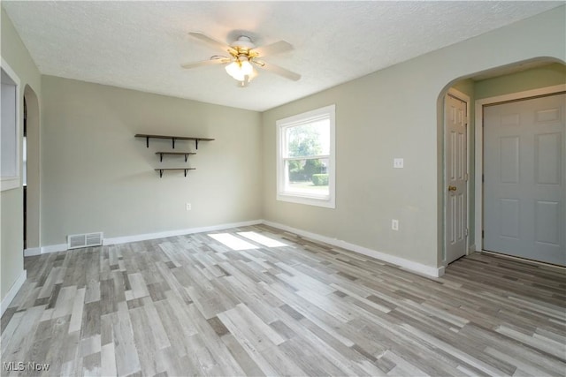 1214 E 360th St, Eastlake, OH 44095 - empty room with arched walkways, a ceiling fan, wood finished floors, and a textured ceiling