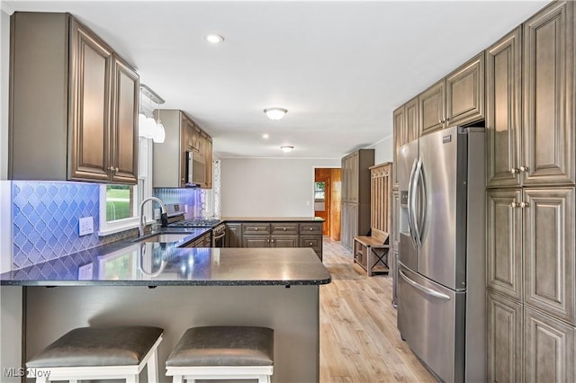 6767 Chippewa Ave NW, North Canton, OH 44720 - kitchen featuring appliances with stainless steel finishes, a peninsula, light wood-style floors, tasteful backsplash, and recessed lighting