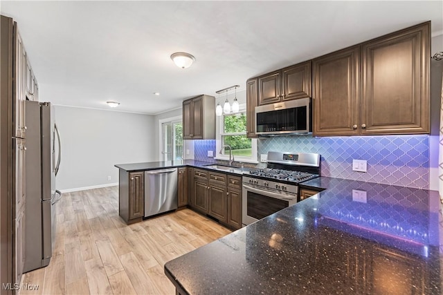6767 Chippewa Ave NW, North Canton, OH 44720 - kitchen with appliances with stainless steel finishes, a peninsula, backsplash, dark stone countertops, and light wood finished floors