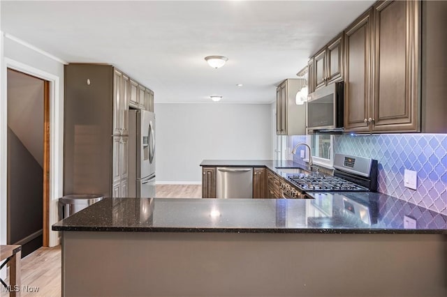 6767 Chippewa Ave NW, North Canton, OH 44720 - kitchen with appliances with stainless steel finishes, a peninsula, backsplash, dark stone countertops, and light wood-style floors