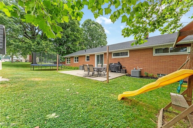 6767 Chippewa Ave NW, North Canton, OH 44720 - rear view of house featuring a trampoline, a patio area, a playground, a lawn, and brick siding