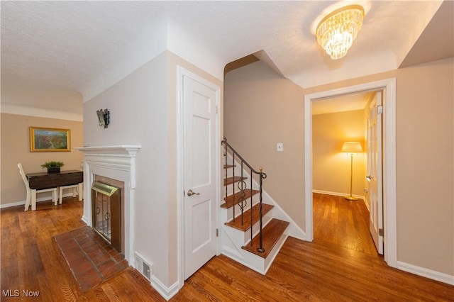 29504 Cresthaven Dr, Willowick, OH 44095 - stairs featuring wood finished floors, a fireplace with raised hearth, and a chandelier