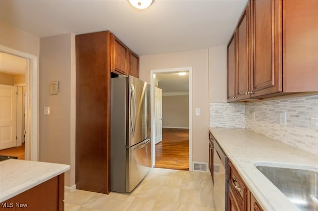 29504 Cresthaven Dr, Willowick, OH 44095 - kitchen with appliances with stainless steel finishes, brown cabinets, backsplash, and light stone countertops