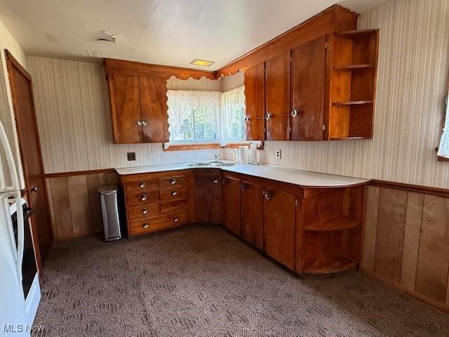 5783 Eagle Creek Rd, Leavittsburg, OH 44430 - kitchen featuring open shelves, brown cabinetry, light countertops, dark carpet, and wooden walls
