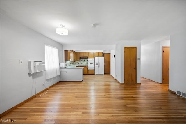 4031 Suffolk Rd, South Euclid, OH 44121 - kitchen with white refrigerator with ice dispenser, light wood-type flooring, brown cabinets, an AC wall unit, and light countertops